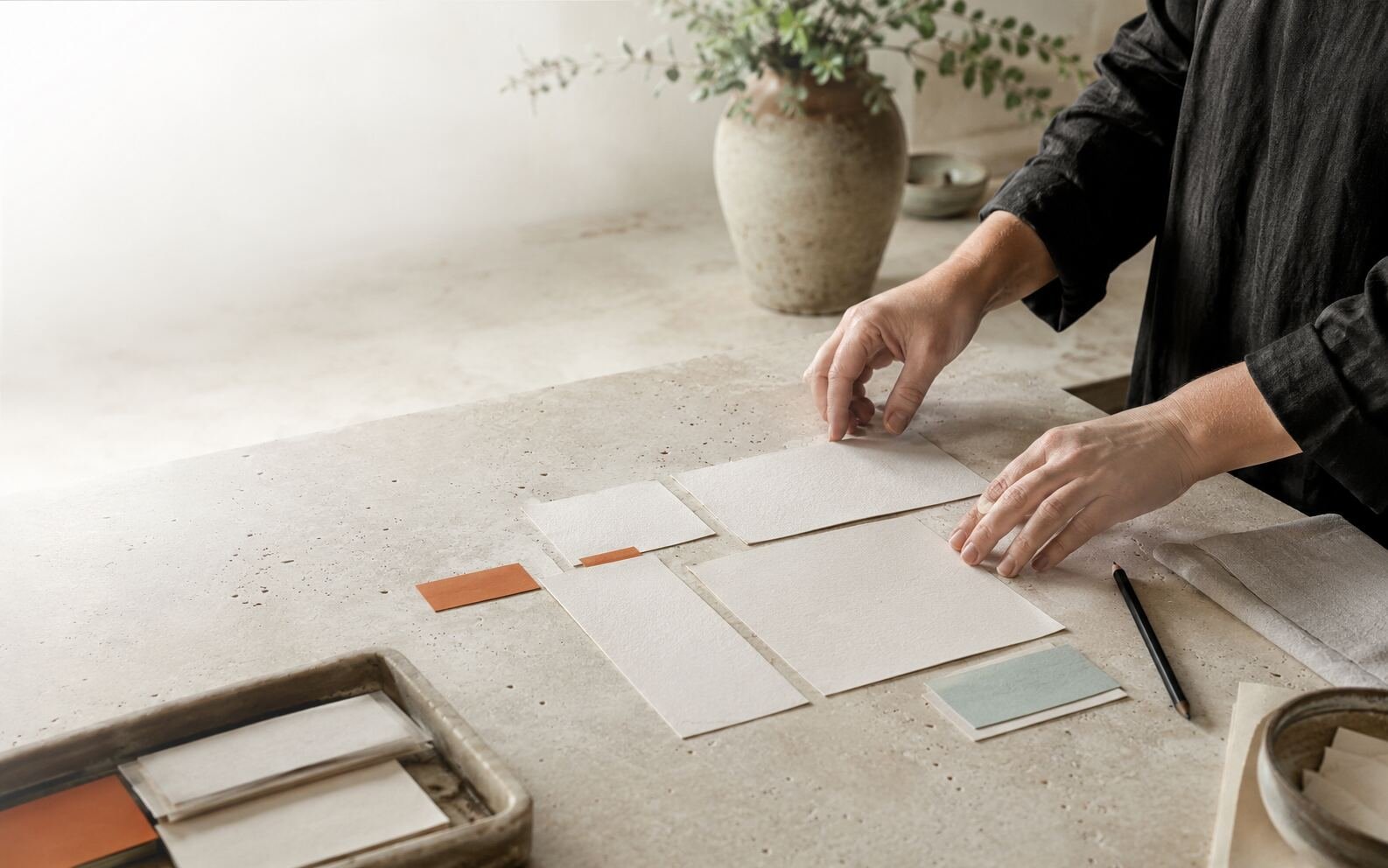 Hands arranging blank paper modules and colored tabs on a studio worktable