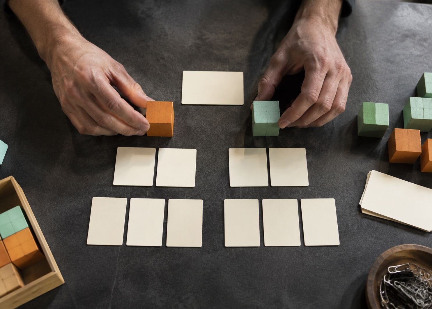 Hands arranging wooden blocks and blank cards into a website structure sequence